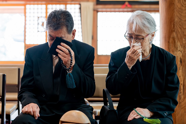 お葬式で泣く高齢者の男女